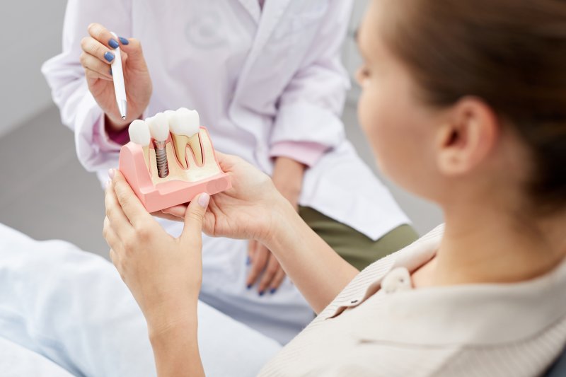 A patient holding a model of dental implant