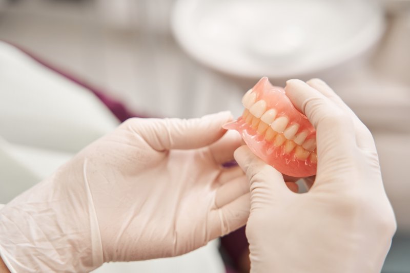 Gloved hands holding a pair of dentures