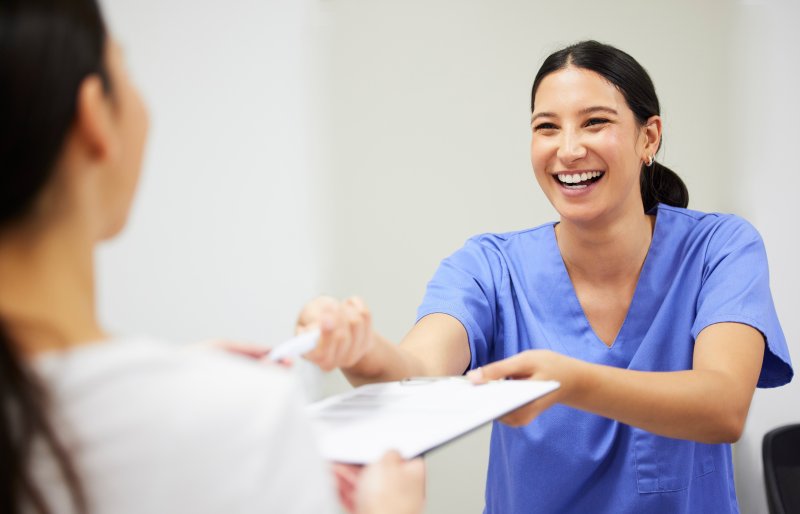 A nurse giving a dental insurance form to a patient